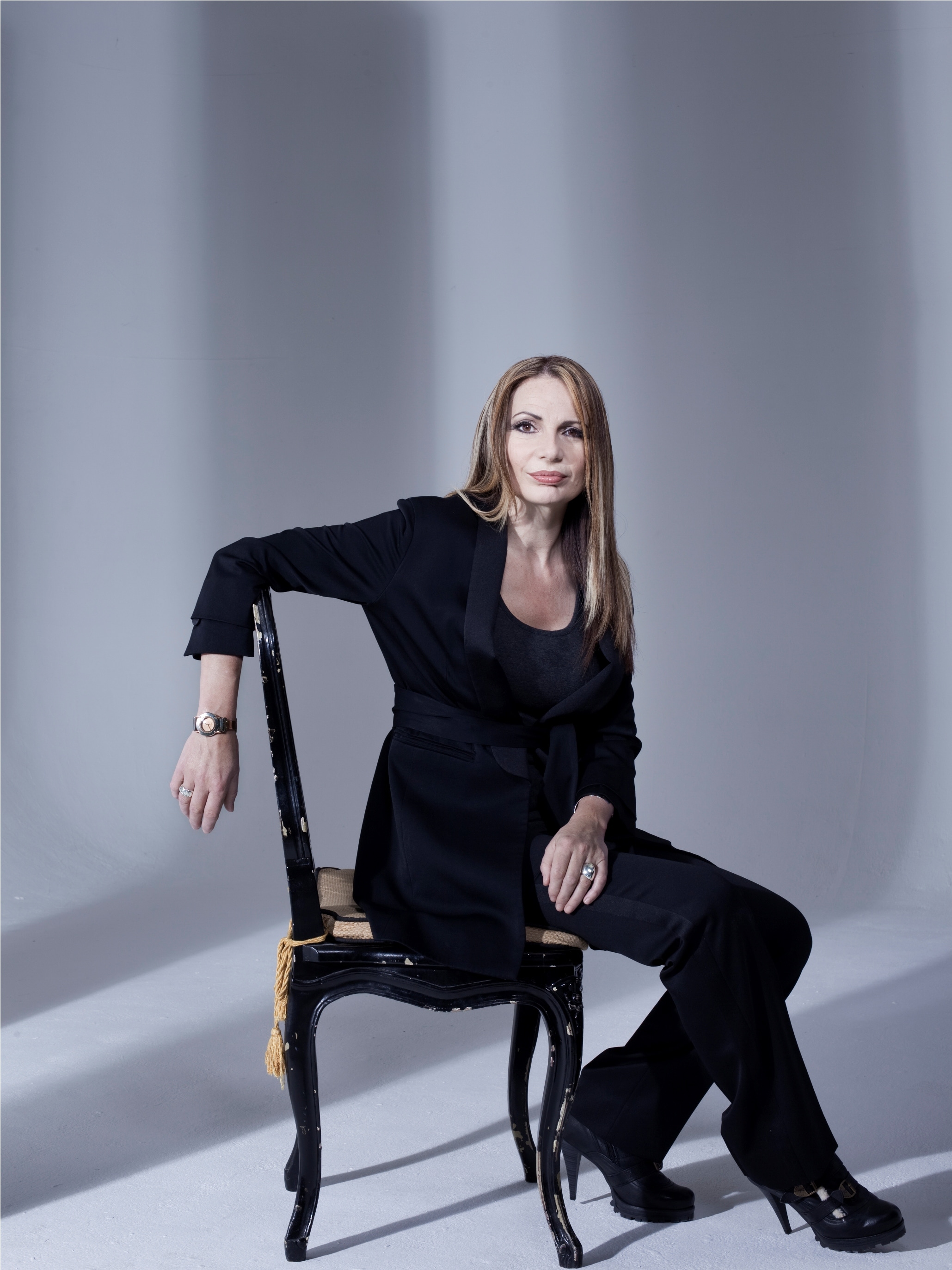 Joanna sat on a chair in front of a plain grey background